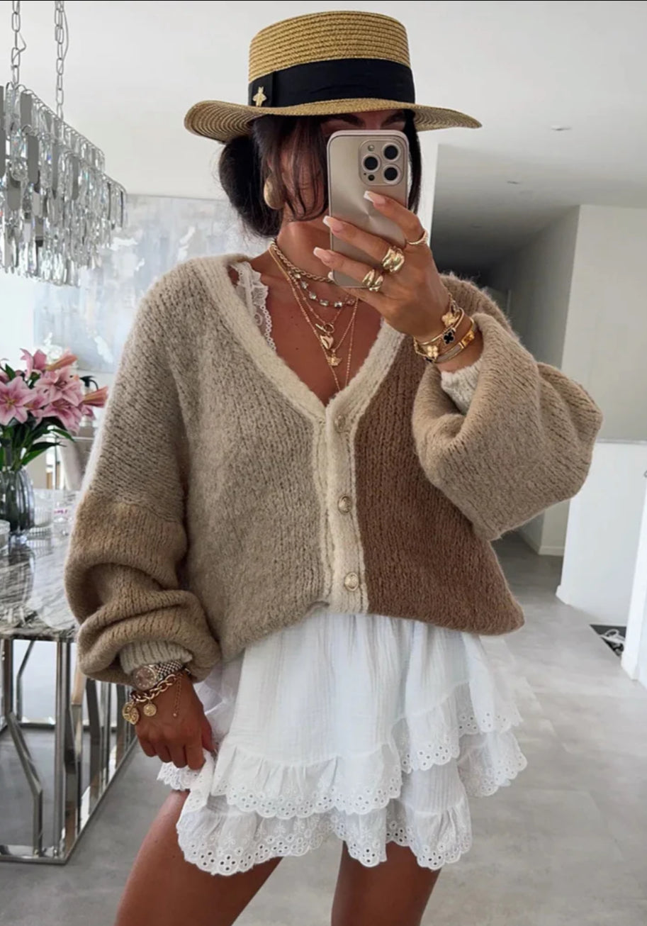 Person wearing a beige cardigan, white lace dress, and straw hat indoors.